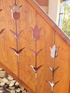 a wooden stair case with metal flowers on the front and side panels, along with wood logs