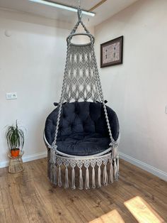 a hanging chair in the corner of a room with wood flooring and white walls