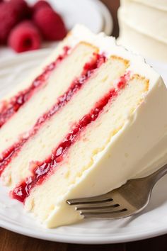 a slice of cake with white frosting and raspberry topping