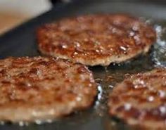 three hamburger patties cooking in a frying pan