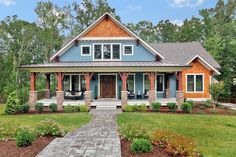 a blue and orange house with stone walkway leading up to the front door is surrounded by greenery