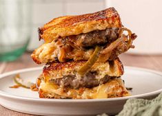 two grilled cheeseburgers stacked on top of each other in a white plate