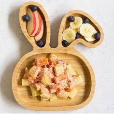 a wooden plate topped with pasta and fruit covered in an animal's ears shape