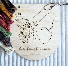 a wooden ornament with a butterfly on it and thread spools next to it