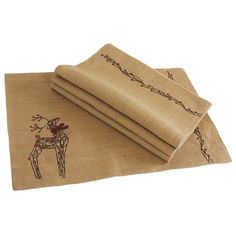 two burlap placemats with embroidered deer on them, one is folded and the other has a brown border