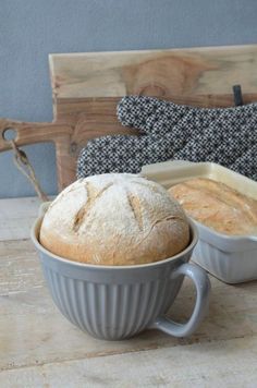 a loaf of bread sitting in a bowl next to a loaf of bread on a table