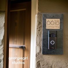 a camera mounted to the side of a stone wall next to a door with a sign on it