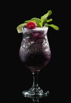 a drink with ice and raspberries in a glass on a black background photo