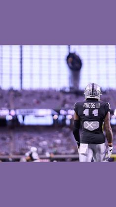 a football player is standing on the field with his hands in his pockets and looking off into the distance