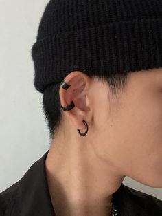 a man with ear piercings wearing a black hat