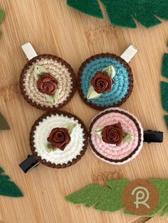 three crocheted cupcakes sitting on top of a wooden table next to green leaves