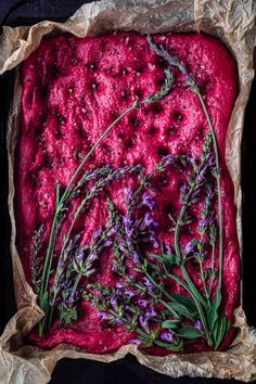 some purple flowers are placed on top of the red food that is covered in wax paper