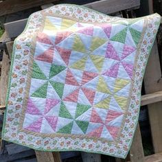 a quilted blanket sitting on top of a wooden bench next to a pile of wood