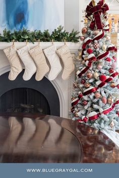 a decorated christmas tree with stockings hanging from it's sides in front of a fireplace