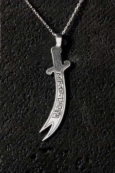 Embrace a piece of history and valor with the Zulfiqar Sword Pendant Necklace, featuring the powerful inscription: "There is No Sword Except Zulfiqar, There is No Brave Except Ali." This striking necklace showcases a detailed Zulfiqar sword design, a symbol of courage and righteousness. Crafted from high-quality sterling silver, the pendant captures the iconic double-edged sword with meticulous craftsmanship, reflecting its historical and symbolic significance. The inscription on the pendant pays homage to Ali ibn Abi Talib, renowned for his bravery and the legendary Zulfiqar sword. The detailed engraving adds a personal touch, making it a meaningful accessory for those who admire historical symbols of heroism. Whether you're looking for a unique piece of jewelry or a thoughtful gift that Zulfiqar Pendant, Thoughtful Gifts, Unique Pieces, Sterling Silver Jewelry, Brave, Jewelry Necklace Pendant, Silver Jewelry, Accessory Gift, Jewelry Necklaces