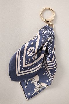 a blue and white bandana hanging on a wall with a gold keychain