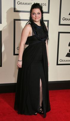 a woman in a long black dress on the red carpet at an awards event,