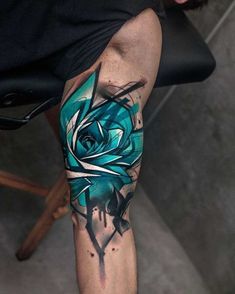 a man's leg with a blue rose tattoo on it and black ink splots