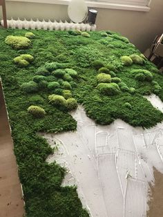 a bed covered in green moss with white sheets on the bottom and one sheet that has been cut off