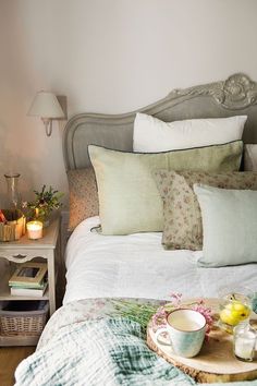 a bed with white linens and pillows on top of it next to a table