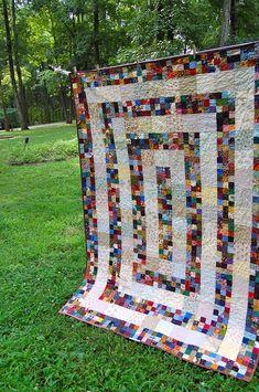 a quilt is hanging on a clothes line in the grass with trees in the background