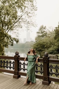 a woman in a green dress leaning on a fence