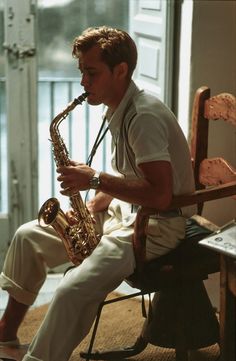 a man sitting in a chair playing a saxophone