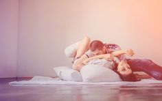 a man and woman laying on a bed with their arms around each other as they hug