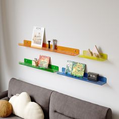 three bookshelves on the wall above a couch with a stuffed animal sitting on it