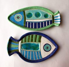 two blue and green fish shaped plates sitting on top of a table