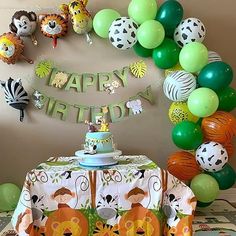 an animal themed birthday party with balloons, cake and table cloths on the table