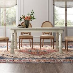 a dining room table with chairs and a vase filled with flowers on top of it