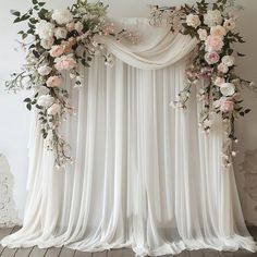 a white drape with flowers and greenery on it in front of a wall