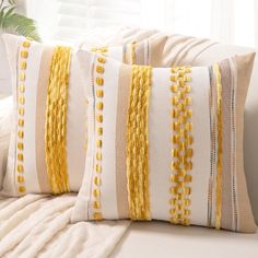 two yellow and white pillows sitting on top of a couch next to a window sill