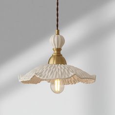 a white and gold light hanging from a ceiling fixture with a brown cord attached to it