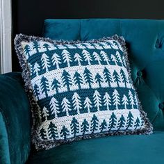 a blue couch with a crocheted christmas tree pillow on it's back