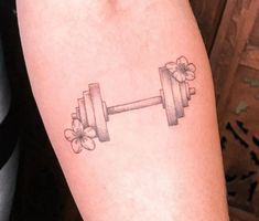 a woman with a tattoo on her arm has a dumbbell and clovers in the shape of flowers