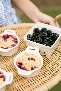 berries and other desserts are sitting on a wicker table with a person holding the tray