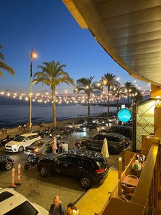 a parking lot filled with lots of parked cars next to the ocean at night time