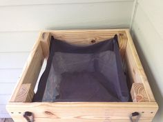 a wooden box filled with black cloth on the side of a house's wall