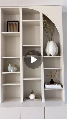 a white bookcase with shelves and vases on it