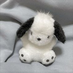 a white and black stuffed animal sitting on top of a bed