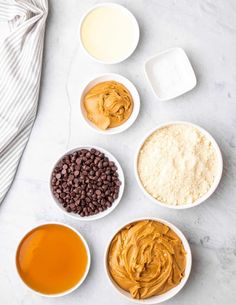 bowls filled with different types of food on top of a white counter next to an oven mitt