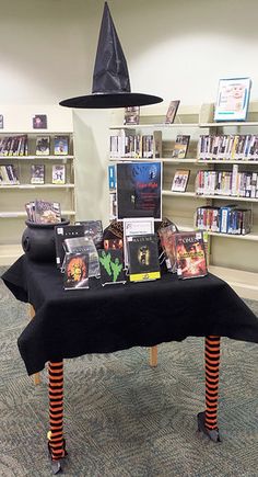 there is a table with books on it and a witch's hat on top