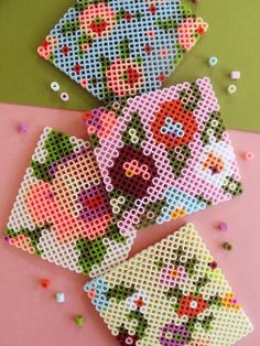 three pieces of beaded art sitting on top of a pink table next to sprinkles