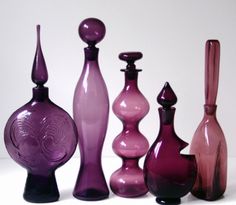 five different colored glass vases lined up in a row