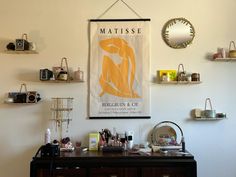 a poster hangs on the wall next to a dresser with various cosmetics and other items