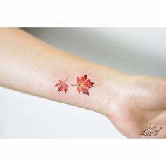 a woman's foot with a red maple leaf tattoo on it