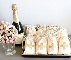 a bottle of wine and some bags with flowers in them on a table next to a vase