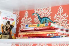 books are stacked on top of each other in front of a wallpapered background